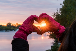 Heart shaped hand looking into the sunset